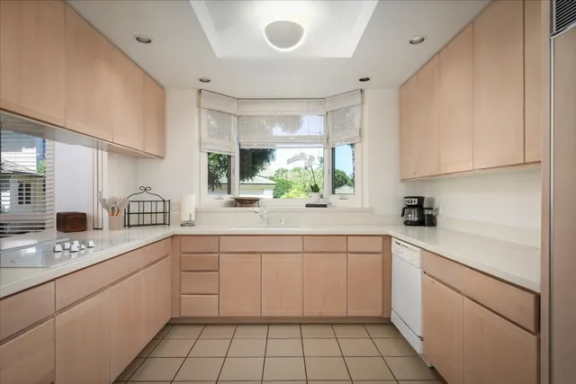a kitchen with a sink dishwasher a stove and white cabinets
