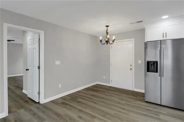 a view of a hallway with wooden floor and chandelier