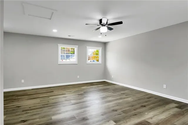 a view of an empty room with wooden floor and window