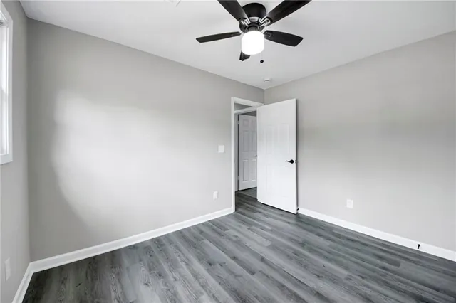 an empty room with wooden floor and fan