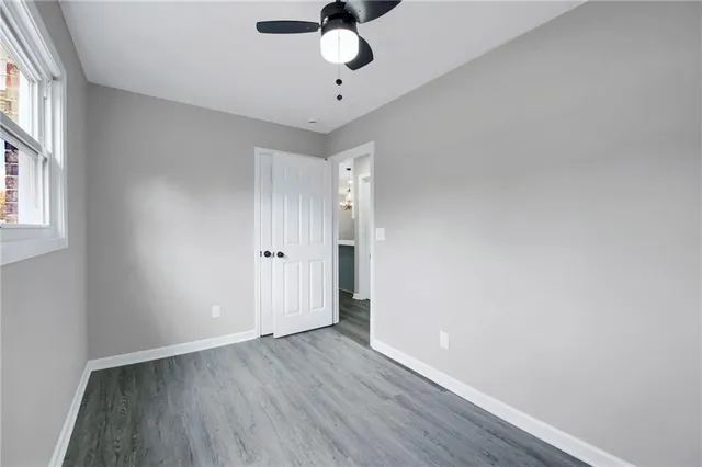 a view of an empty room with window and wooden floor