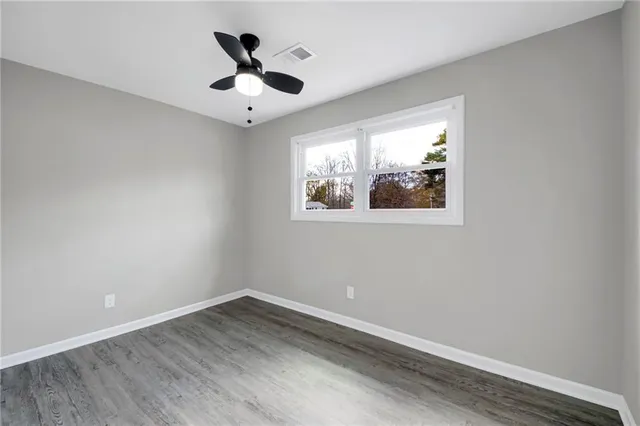 an empty room with wooden floor and ceiling fan