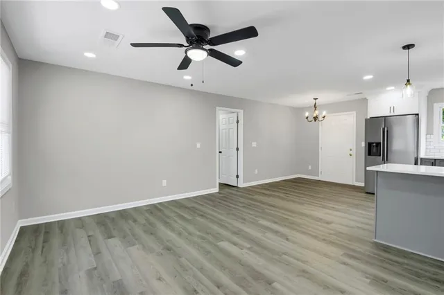 an empty room with wooden floor and a ceiling fan