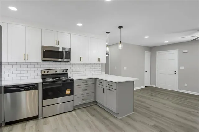 a large kitchen with stainless steel appliances granite countertop a stove a sink and a microwave