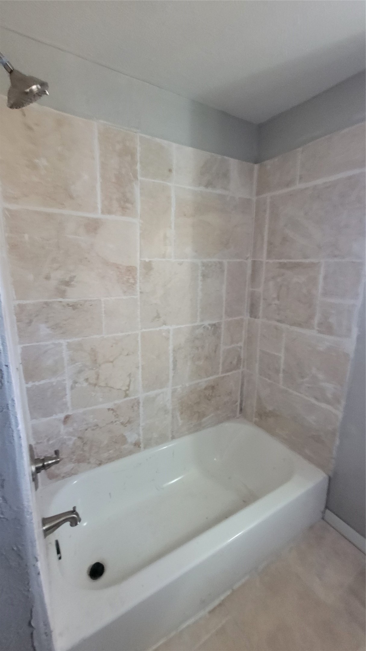 12018 Sandpiper Road Angleton, TX 77515 - Photo 26 of 48 This bathroom features a classic white bathtub with sleek fixtures, surrounded by beige tiled walls for a clean and neutral look.