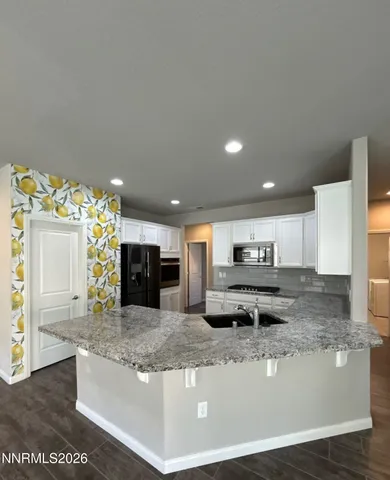 a kitchen with granite countertop a sink stainless steel appliances and white cabinets