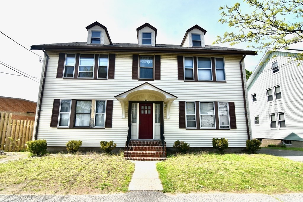 a view of a brick house with large windows and a small yard