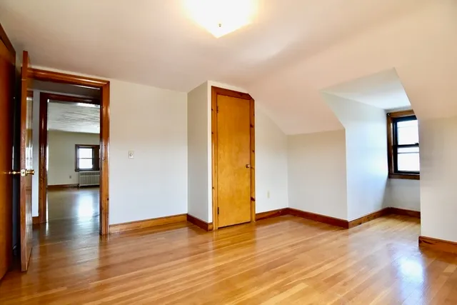 a view of an empty room with wooden floor and closet