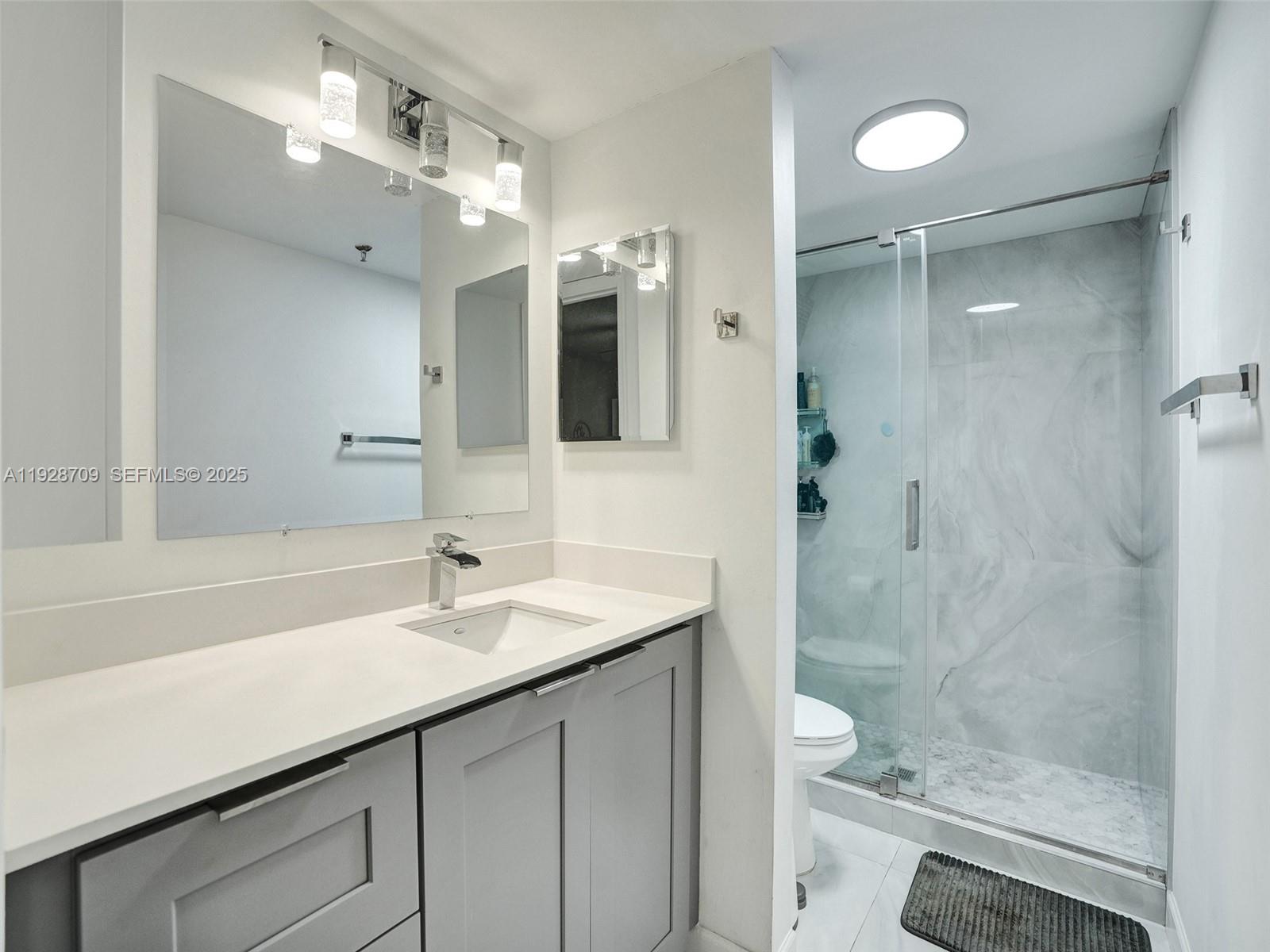 9470 Tangerine Place, Unit 207 Davie, FL 33324 - Photo 11 of 14 a bathroom with a shower sink vanity mirror and toilet