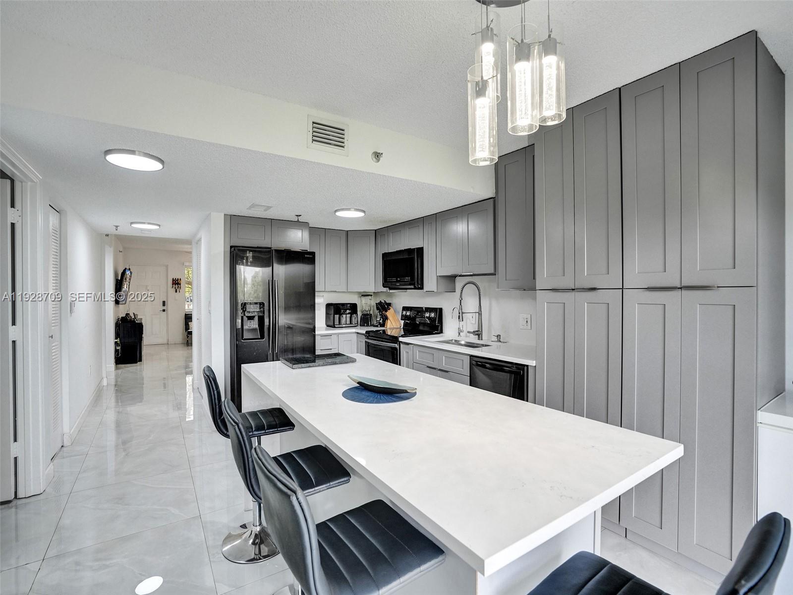 9470 Tangerine Place, Unit 207 Davie, FL 33324 - Photo 8 of 14 a kitchen with kitchen island a sink stove and refrigerator