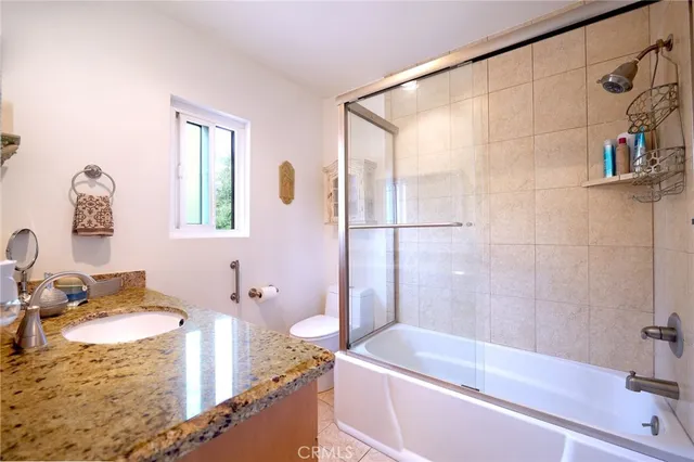 a bathroom with a granite countertop sink a mirror and a bathtub