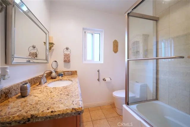 a bathroom with a granite countertop sink a toilet a mirror and shower