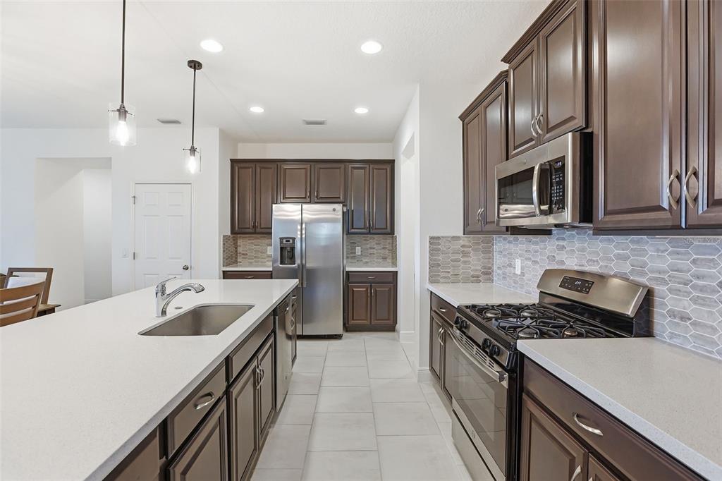 1433 Shira Road Minneola, FL 34715 - Photo 16 of 40 a kitchen with stainless steel appliances granite countertop a sink a stove and a refrigerator