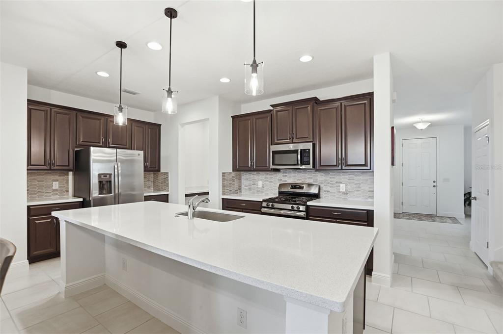 1433 Shira Road Minneola, FL 34715 - Photo 2 of 40 a kitchen with stainless steel appliances a sink a stove a refrigerator center island and cabinets