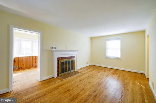 a view of an empty room with wooden floor and a fireplace