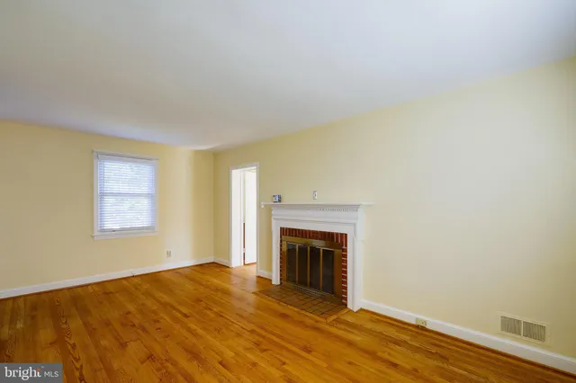 a view of empty room with wooden floor and a fireplace
