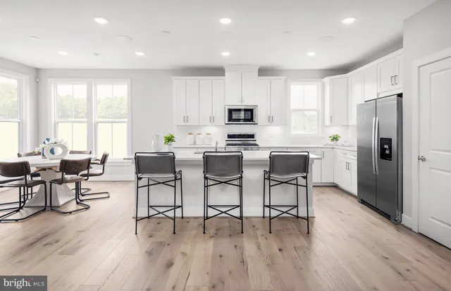 a kitchen with stainless steel appliances a dining table chairs stove refrigerator and cabinets