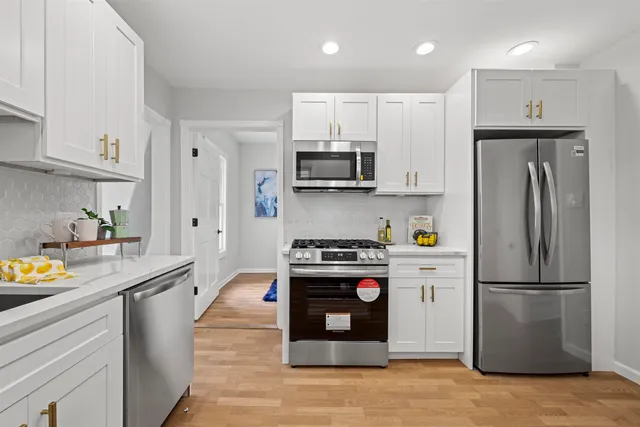 a kitchen with stainless steel appliances granite countertop a refrigerator a stove a sink and a microwave