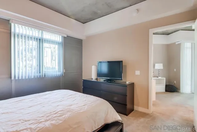 a bedroom with a bed and a flat tv screen on wall