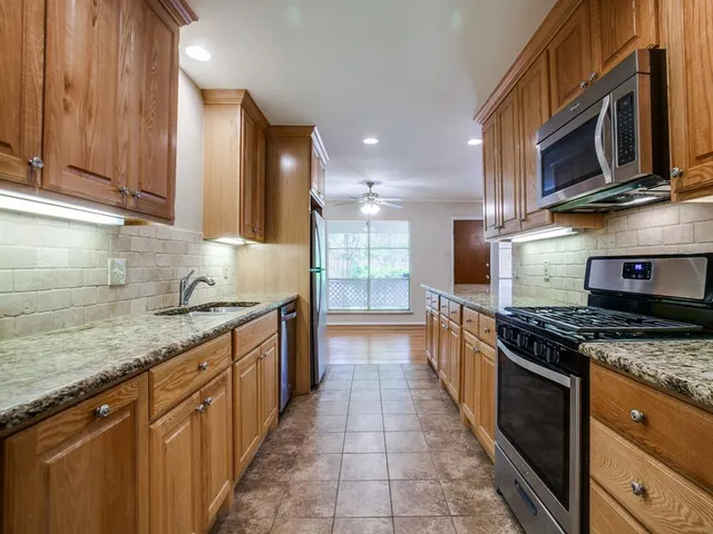 a large kitchen with stainless steel appliances granite countertop a stove a sink and a microwave