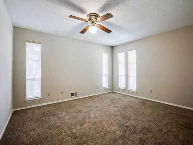 an empty room with window and ceiling fan