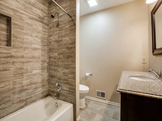 a bathroom with a granite countertop sink toilet and shower