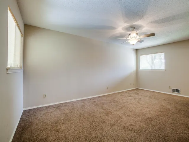 an empty room with windows and chandelier fan