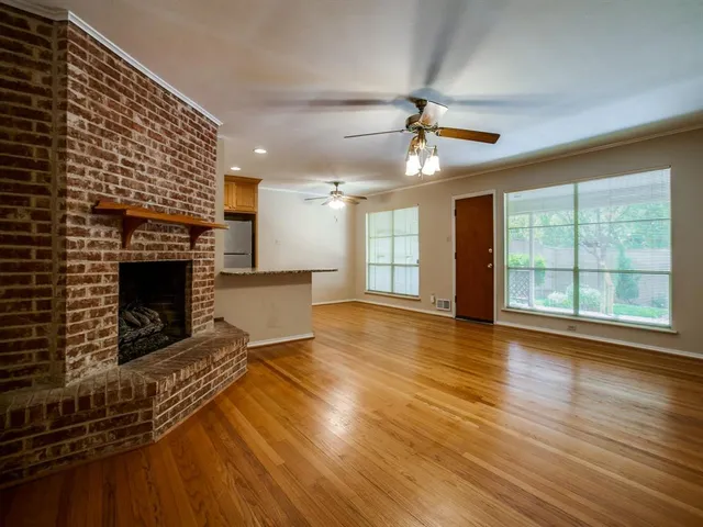 an empty room with wooden floor fireplace and windows