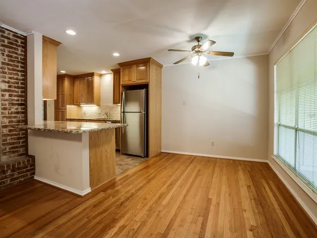 a kitchen with stainless steel appliances granite countertop a sink a stove a refrigerator and island with wooden floor