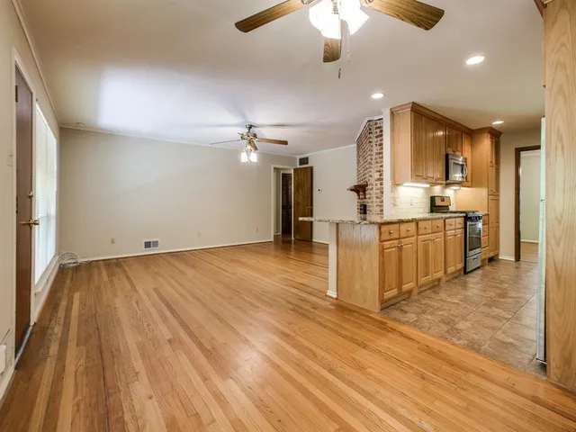 an empty room with kitchen view and wooden floor