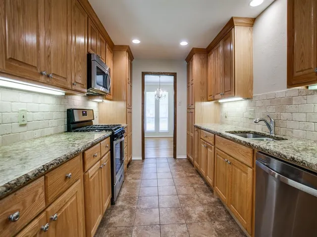 a kitchen with stainless steel appliances granite countertop wooden cabinets a sink and dishwasher