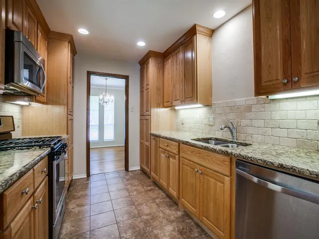 a kitchen with stainless steel appliances granite countertop a stove a sink and a microwave