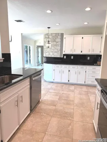 a large kitchen with stainless steel appliances granite countertop a stove a sink and white cabinets