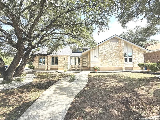 a view of a yard in front of a house with a large tree