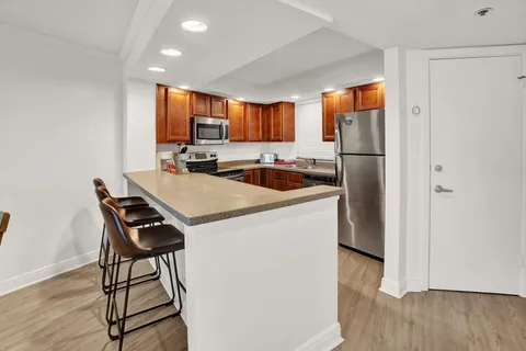 a kitchen with a refrigerator a stove a sink and a dining table with wooden floor