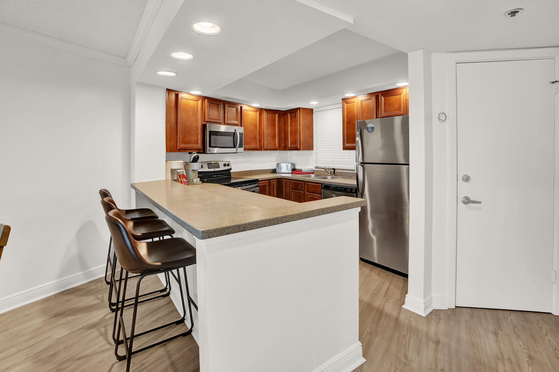 4202 Beachside 2, Unit 202 Miramar Beach, FL 32550 - Photo 9 of 45 a kitchen with a refrigerator a stove a sink and a dining table with wooden floor