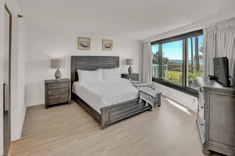 a spacious bedroom with a bed and a flat tv screen on dresser