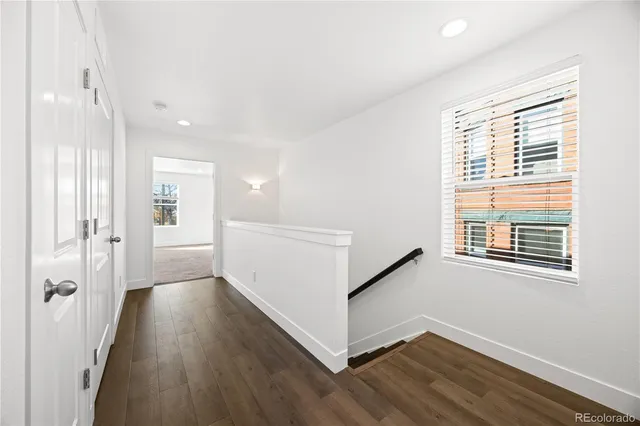a view of a hallway with wooden floor and a bathroom