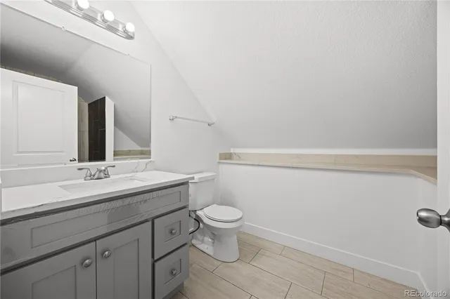 a bathroom with a granite countertop sink a toilet and a mirror