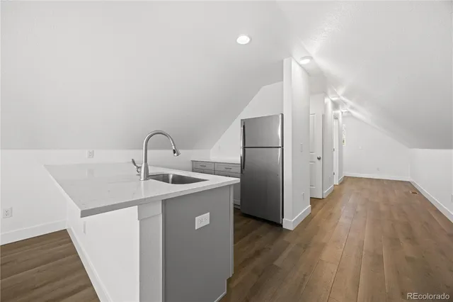 a kitchen with a sink a refrigerator and wooden floor