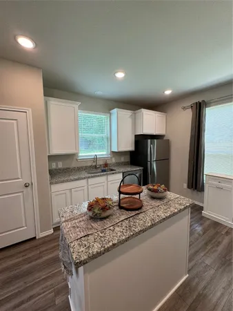 a kitchen with kitchen island granite countertop wooden cabinets a refrigerator and microwave