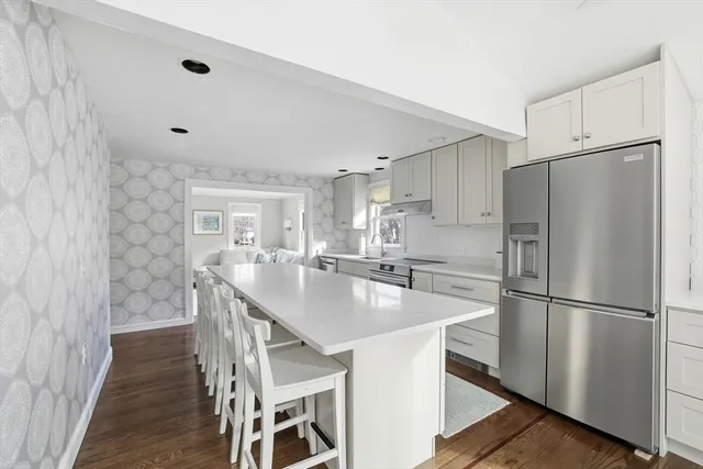 a kitchen with stainless steel appliances a refrigerator a sink a stove a dining table and chairs