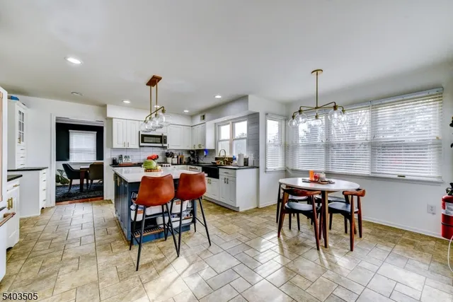 a open kitchen with stainless steel appliances kitchen island granite countertop a table and chairs in it