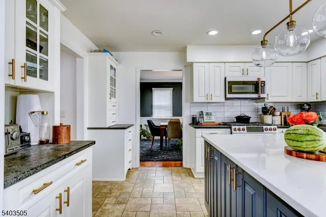 a kitchen with stainless steel appliances granite countertop a stove top oven a sink a microwave and dining table
