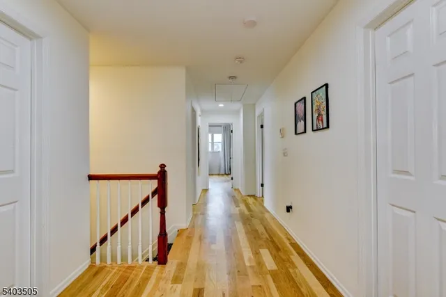 a view of a hallway with wooden floor and staircase