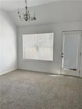 an empty room with a chandelier fan and windows