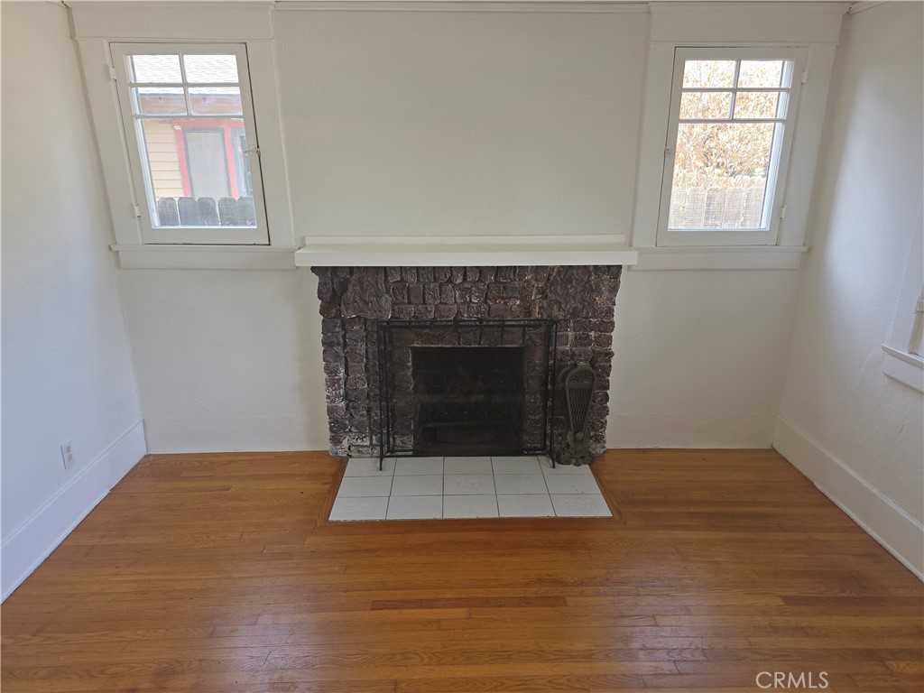 3992 Linwood Place Riverside, CA 92506 - Photo 7 of 9 an empty room with wooden floor a fireplace and windows