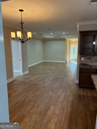 a view of a kitchen and an empty room with wooden floor