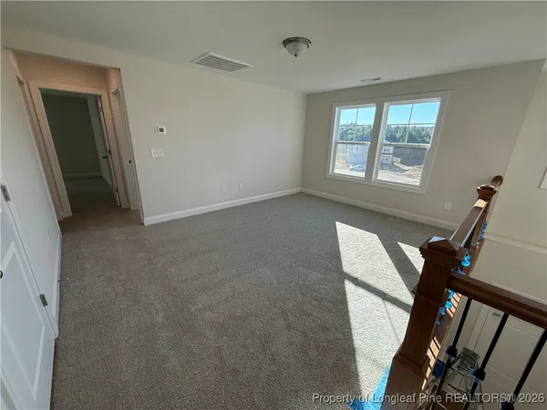 a view of an empty room with furniture and a window