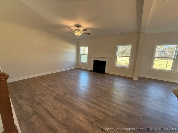 a view of an empty room with a window and wooden floor